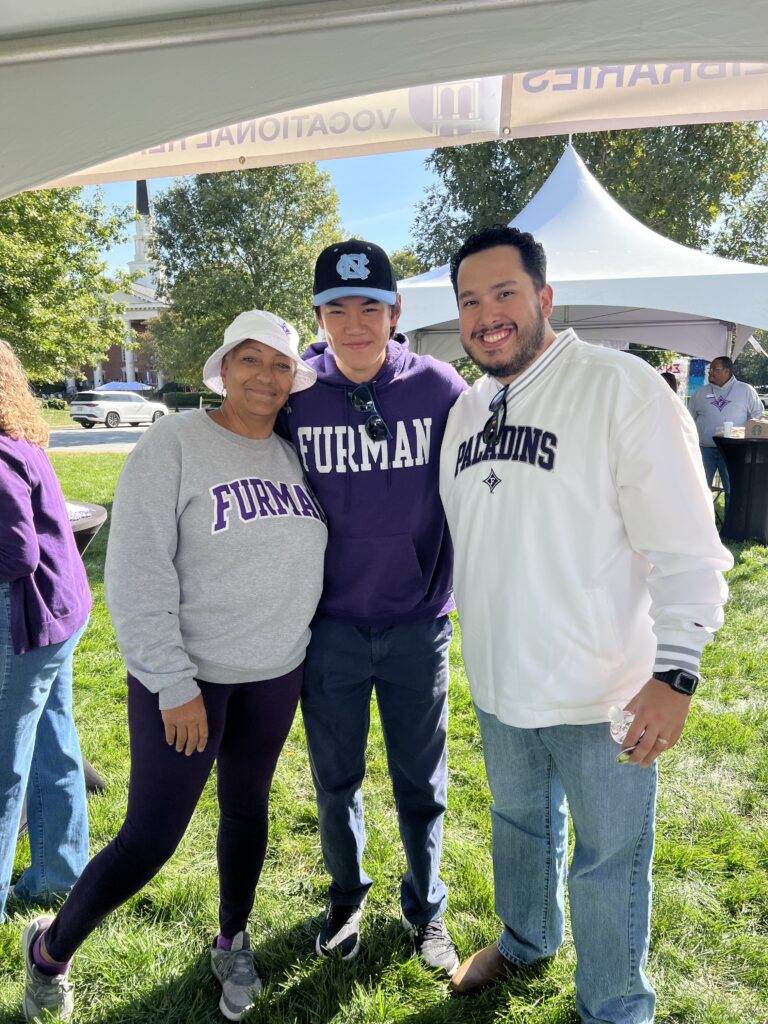 Librarian Robyn Andrews stands smiling with two alumni student assistants.